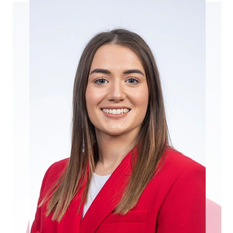 Professional female with brown hair in a red suit